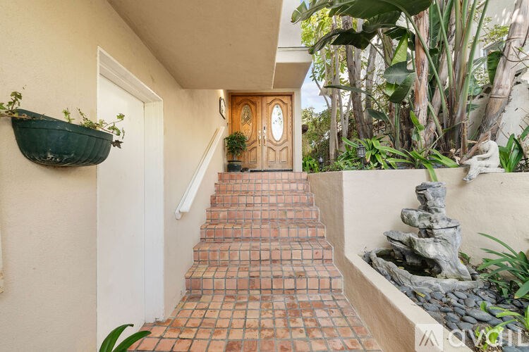 A staircase with a red tile pattern leads to a door with a clock on the wall.