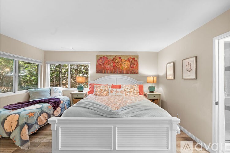 A bedroom with a large bed and a painting on the wall.