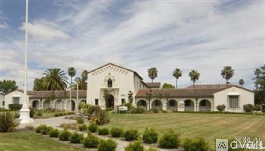 A white building with arches and a flagpole in front.