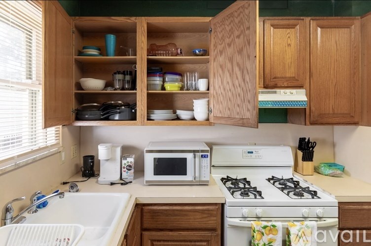A kitchen with a white stove, white microwave, and white sink.