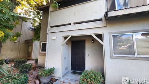 A house with a black door and a window with blinds.