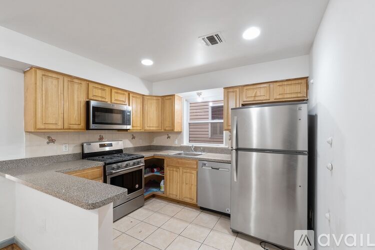 A kitchen with wooden cabinets and a stainless steel refrigerator.