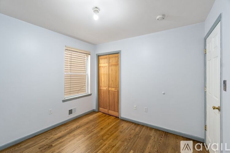 A room with a wooden door and a white wall.