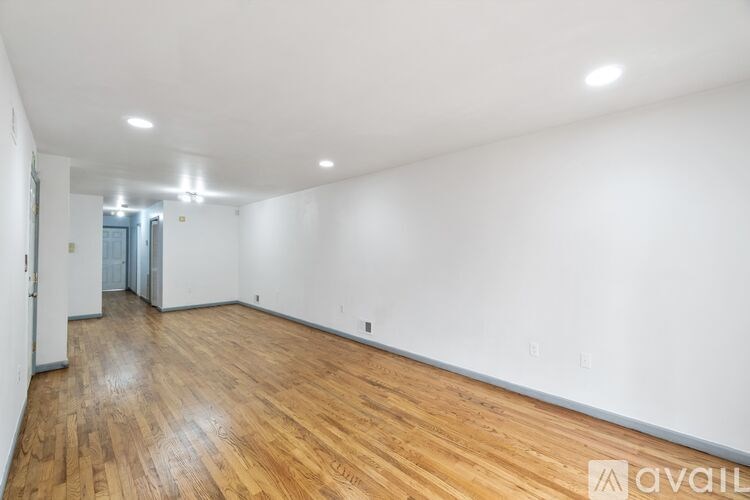 A room with wooden flooring and white walls is available for rent.