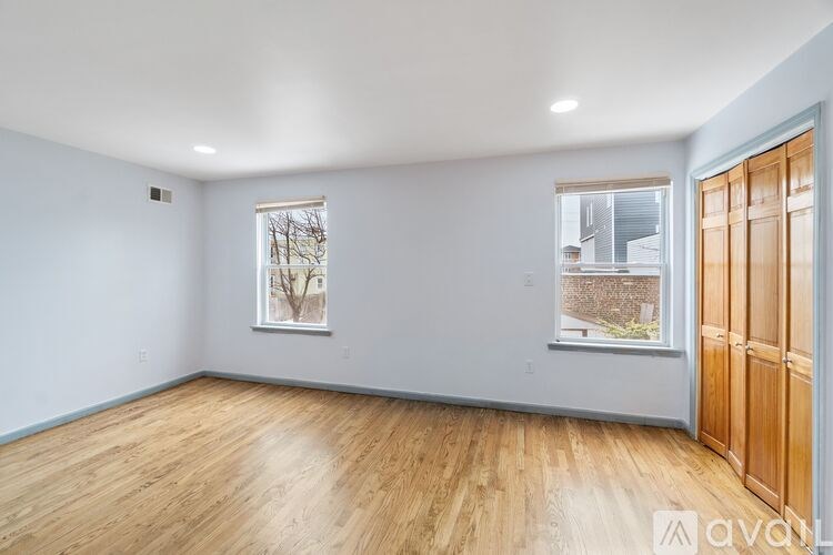 A room with wooden floors and two windows.