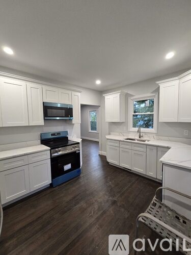 A kitchen with white cabinets and a wooden floor.