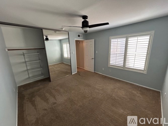 A room with a ceiling fan and a door leading to another room.