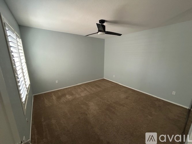 A room with a ceiling fan and a window with blinds.