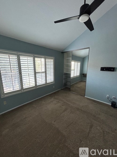 A room with a ceiling fan and a large mirror.