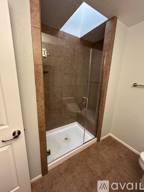 A bathroom with brown tiles and a glass shower door.