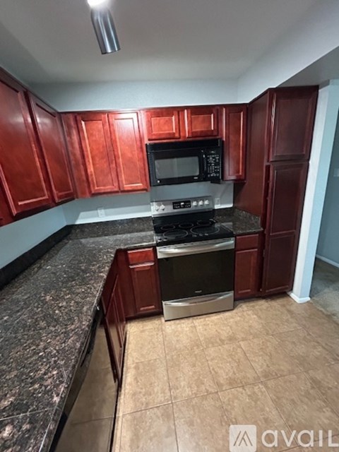 A kitchen with red cabinets and a granite countertop.