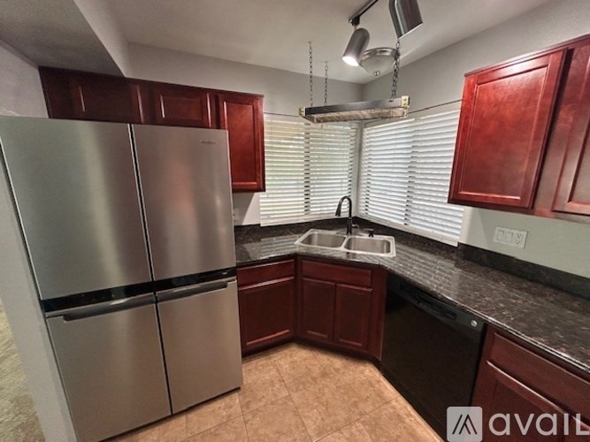 A kitchen with a stainless steel refrigerator and wooden cabinets.