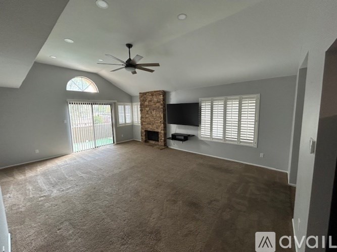 A spacious living room with a fireplace and a ceiling fan.