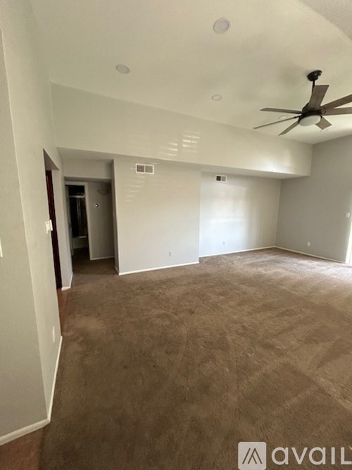A spacious room with a ceiling fan and carpeted floor.