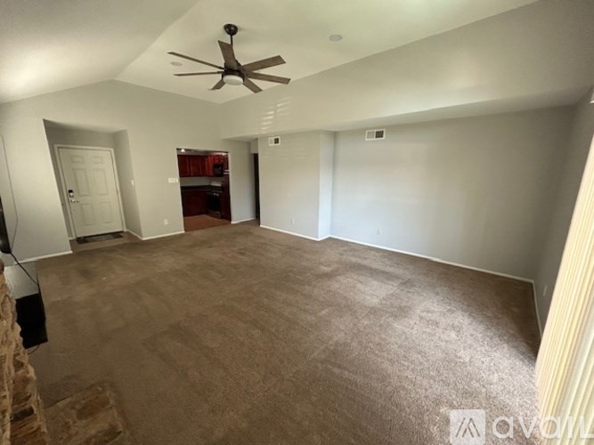 A room with a ceiling fan and carpeted floor.