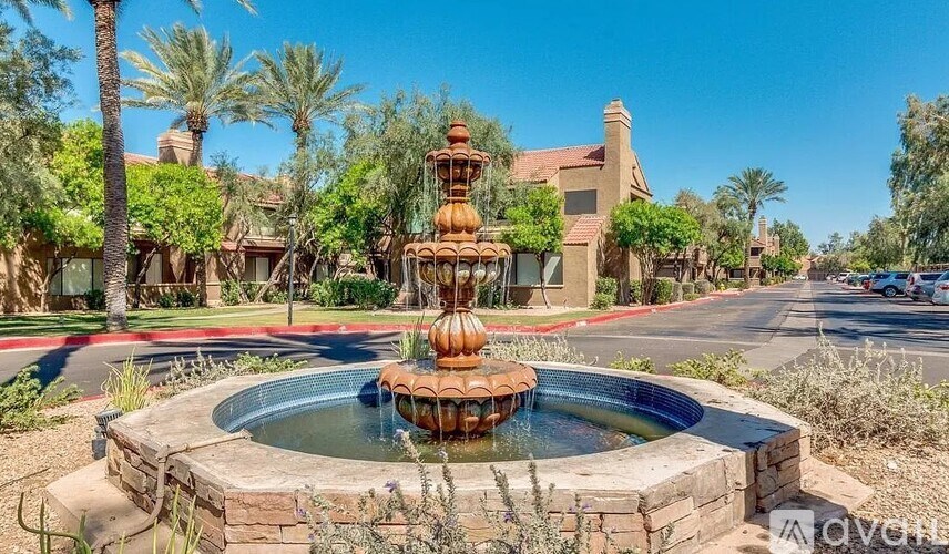 A fountain in the middle of a desert-like landscape with palm trees.