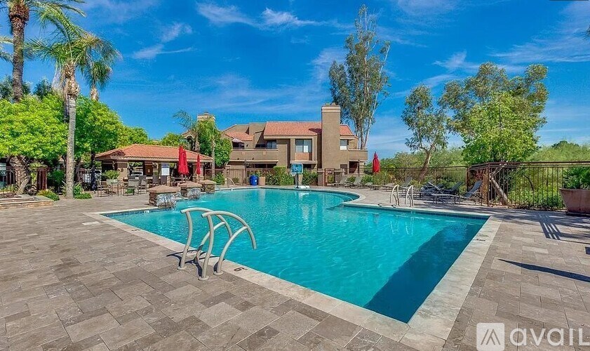 A swimming pool surrounded by a patio and trees.