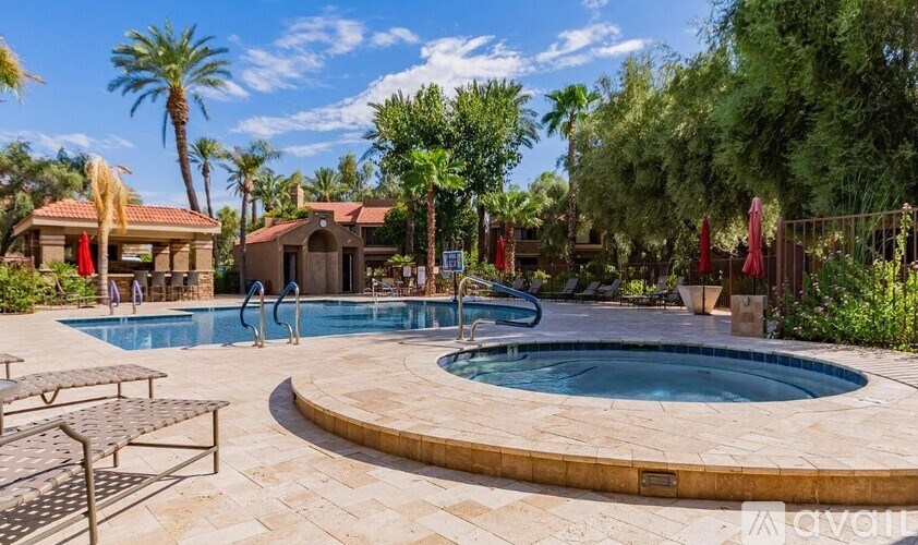 A pool surrounded by palm trees and a patio area with chairs and umbrellas.