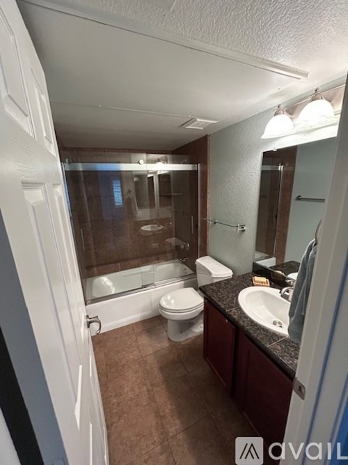 A bathroom with brown tiles and a white toilet.