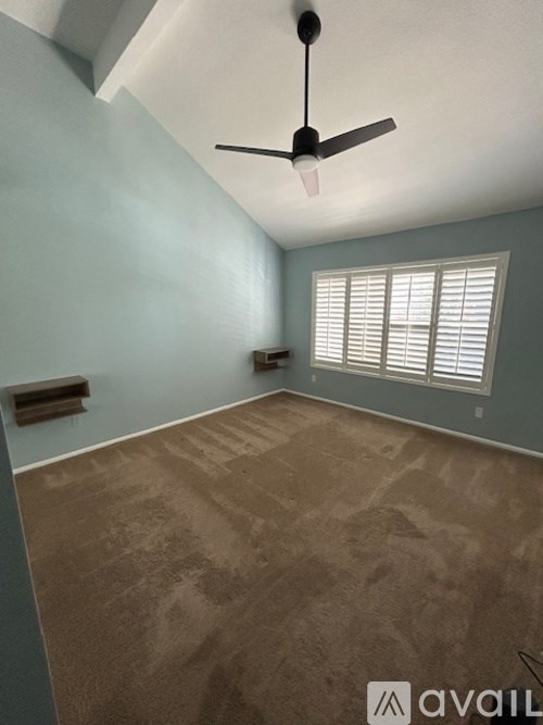 A room with a ceiling fan and carpeted floor.