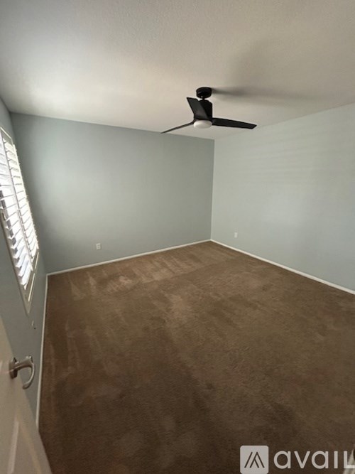 A room with a ceiling fan and carpeted floor.