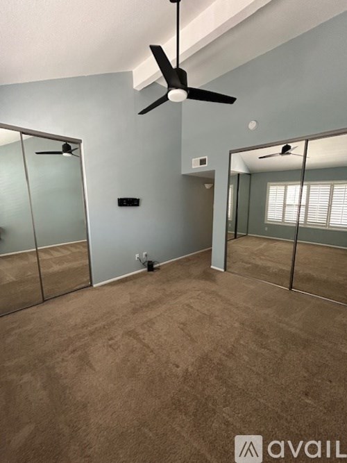 A room with a ceiling fan and a mirror on the wall.