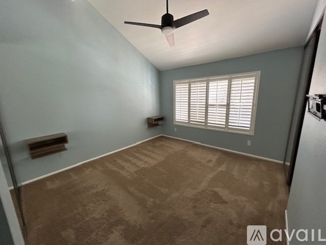 A room with a ceiling fan and a window with blinds.