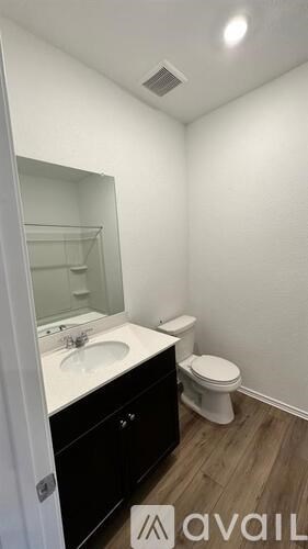 A bathroom with a toilet, sink, and mirror.