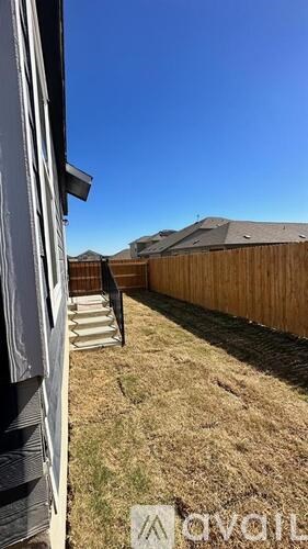 A backyard with a wooden fence and a clear blue sky.
