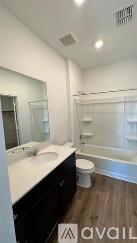 A bathroom with a toilet, sink, mirror and bathtub.