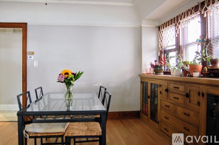 A dining table with chairs and a vase of flowers on it.