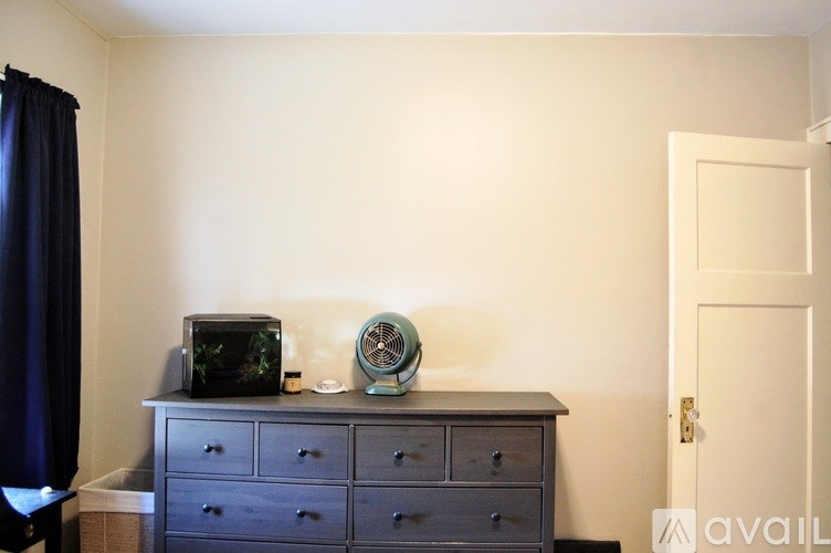 A black dresser with a fish tank and fan on top.
