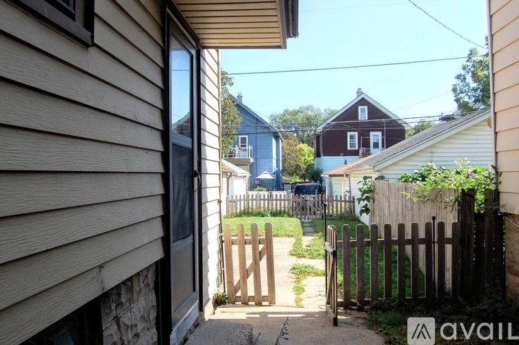 A view from a house looking out to a street with a blue house and a brown house in the background.
