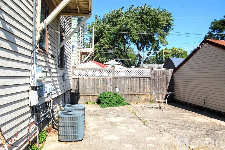 A backyard with a fence, a tree, and a house.