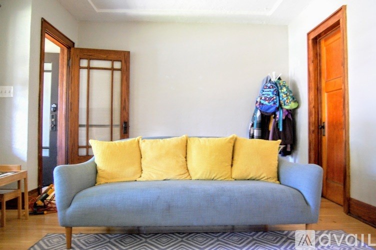 A grey couch with yellow pillows in a room.