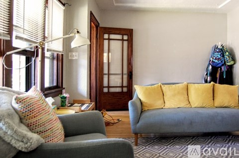 A living room with a grey couch and a yellow cushion.