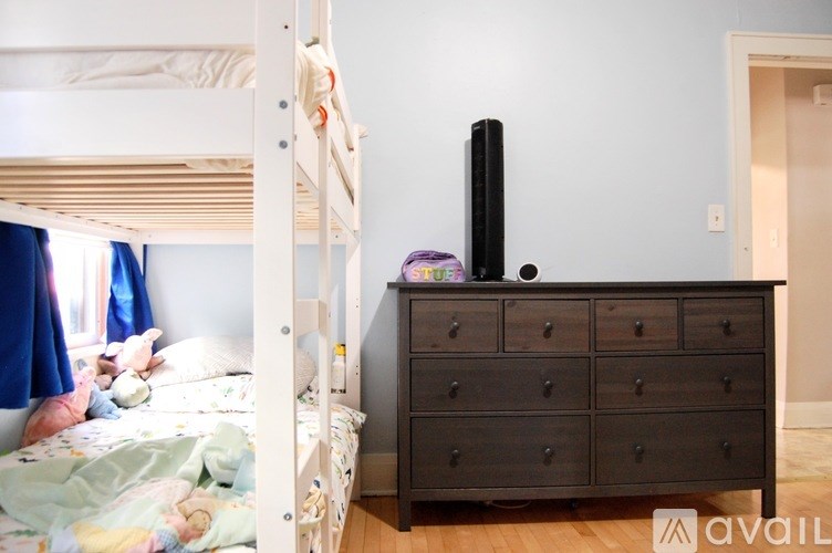 A white bunk bed with a black dresser underneath it.