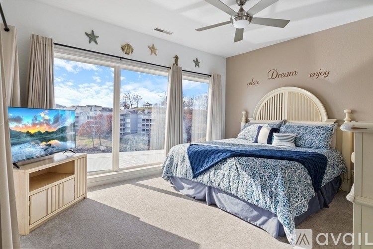 A bedroom with a bed, a television, and a window with a view of a city.