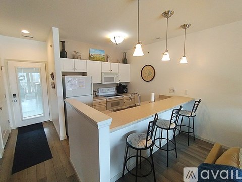 A kitchen with white cabinets and a bar area with stools.