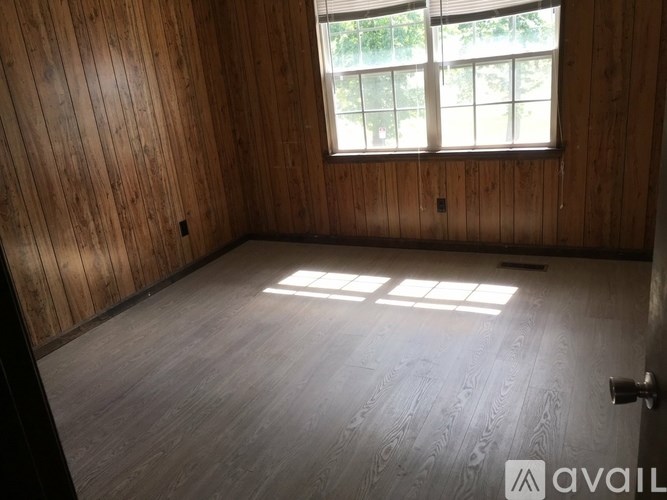 A room with wooden walls and floor and a window.
