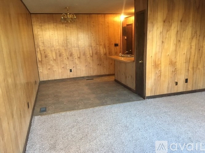 A room with wooden walls and a bathroom area with a sink and mirror.