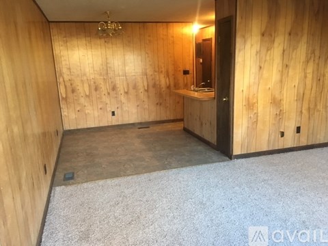 A room with wooden walls and a bathroom area with a sink and mirror.