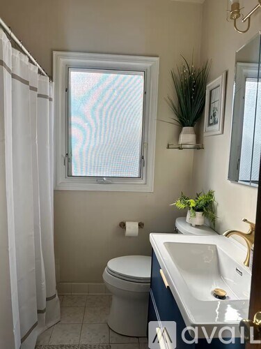 A bathroom with a toilet, sink, and window.