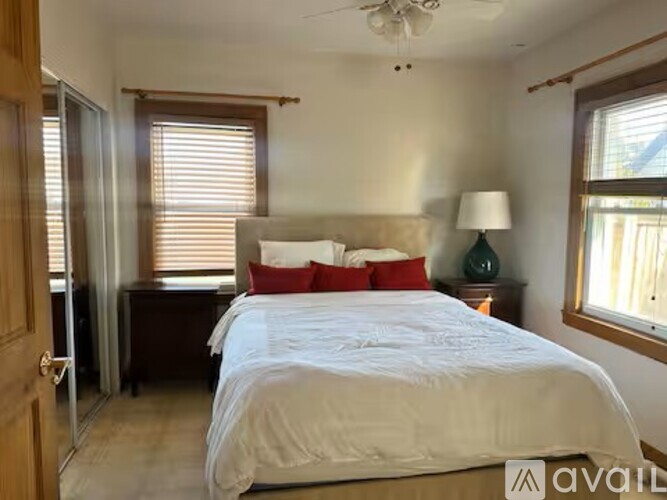 A bedroom with a large bed and a ceiling fan.