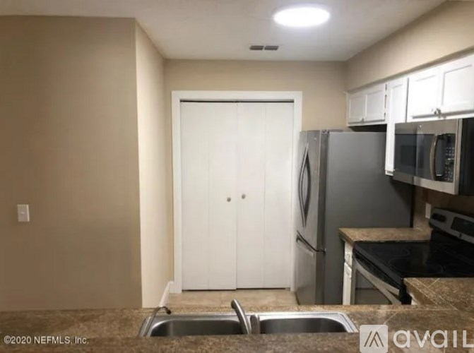 A kitchen with a white door, a sink, and a counter.