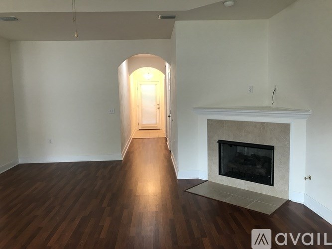A room with a fireplace and a doorway leading to another room.