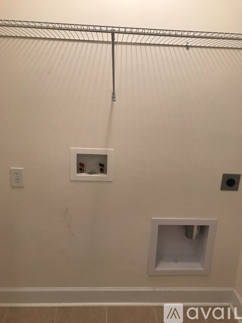 A bathroom with a white wall and a small white square on the wall.