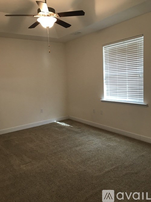 A room with a ceiling fan and a window with blinds.
