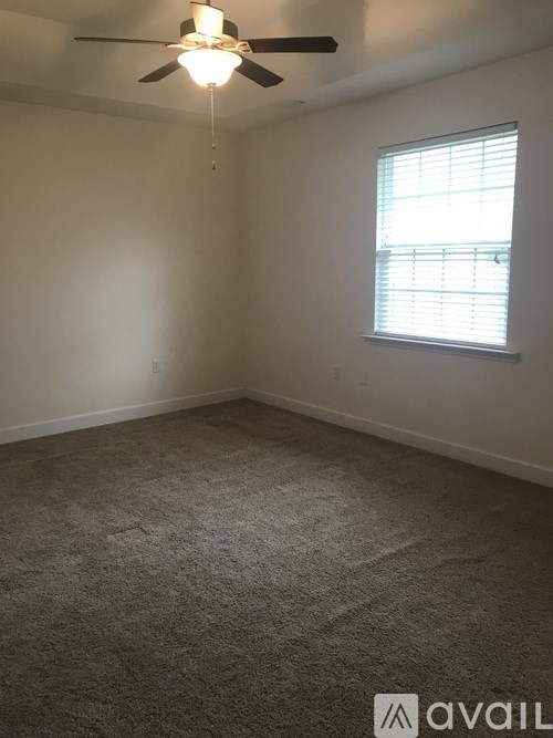A room with a ceiling fan and a window with blinds.