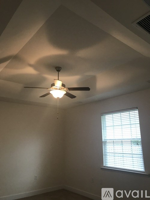 A room with a ceiling fan and a window with blinds.